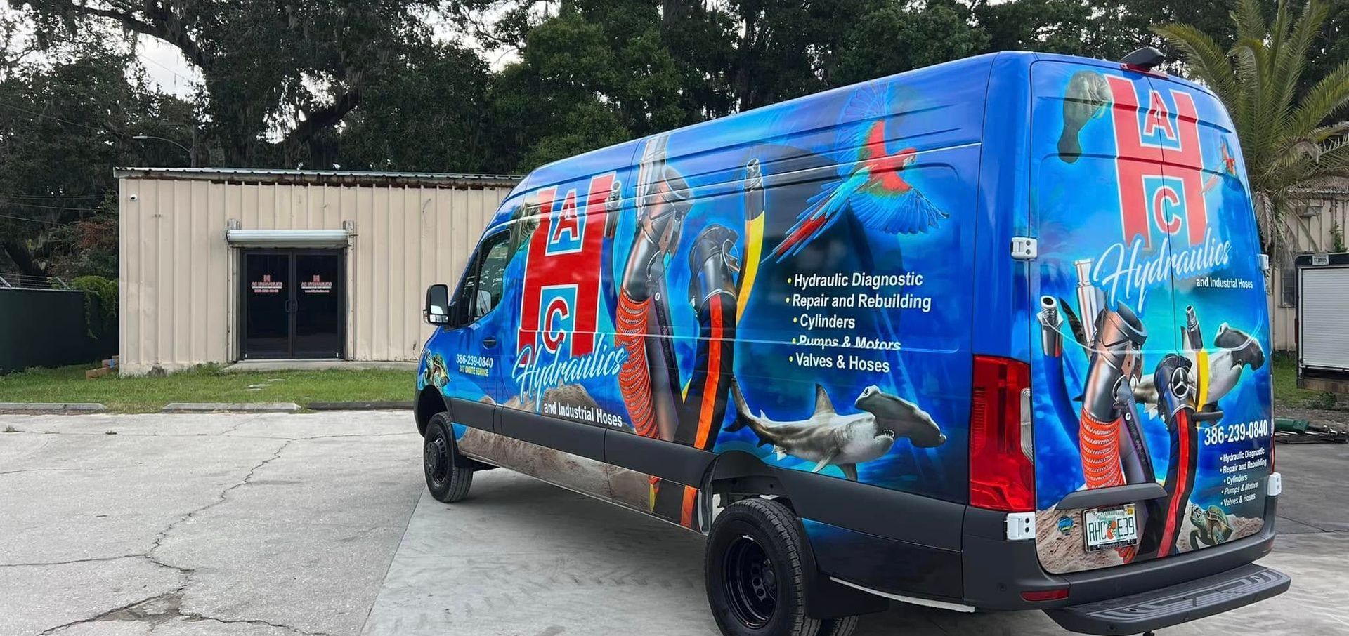 A blue van is parked in a parking lot in front of a building.