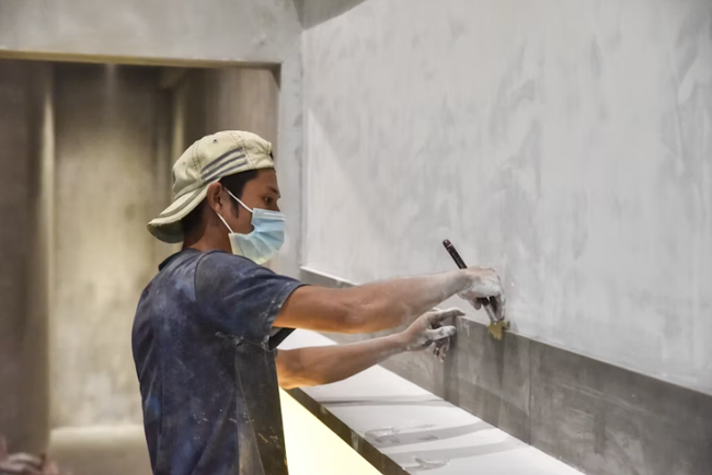 Worker repairing and smoothing a damaged wall surface with joint compound for a drywall contractor in San Tan Valley, AZ