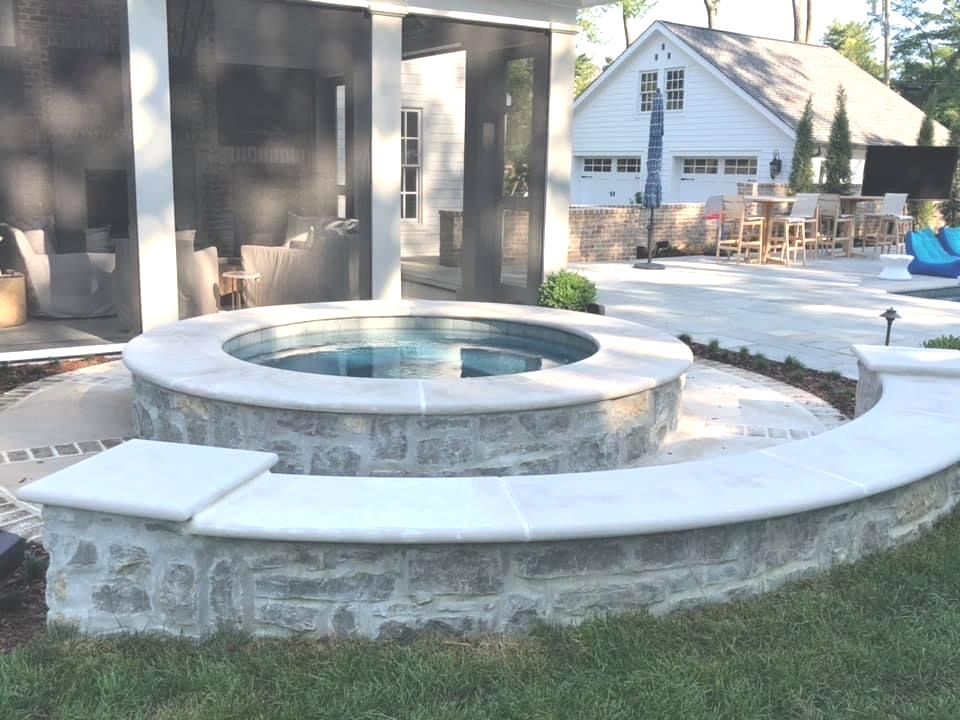 A hot tub in the backyard of a house with a screened in porch.