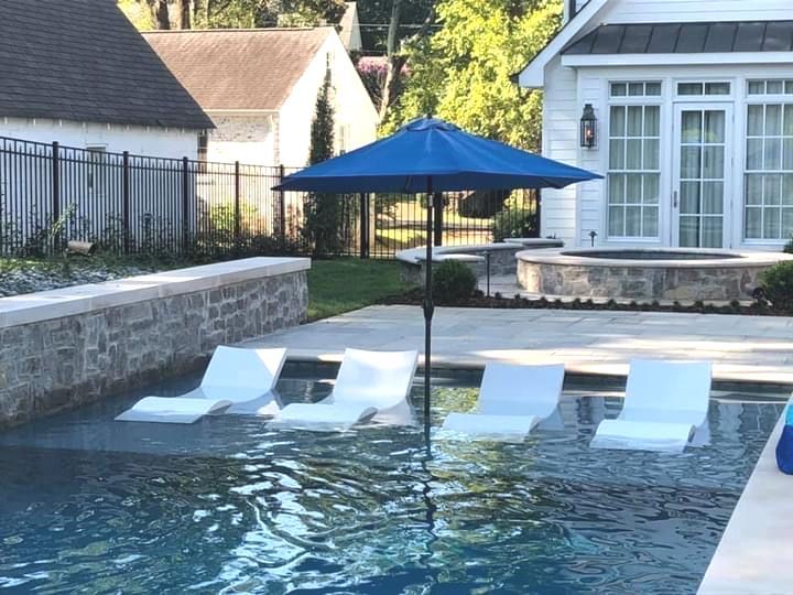 A swimming pool with chairs and an umbrella in front of a house