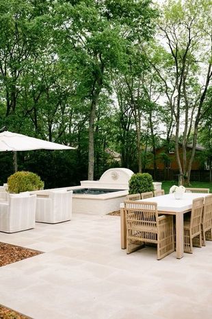 A patio with a table , chairs , umbrellas and a hot tub.