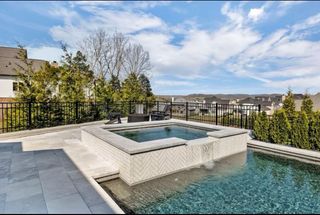 A large swimming pool with a hot tub in the middle of it