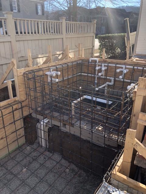 A swimming pool is being built in the backyard of a house.