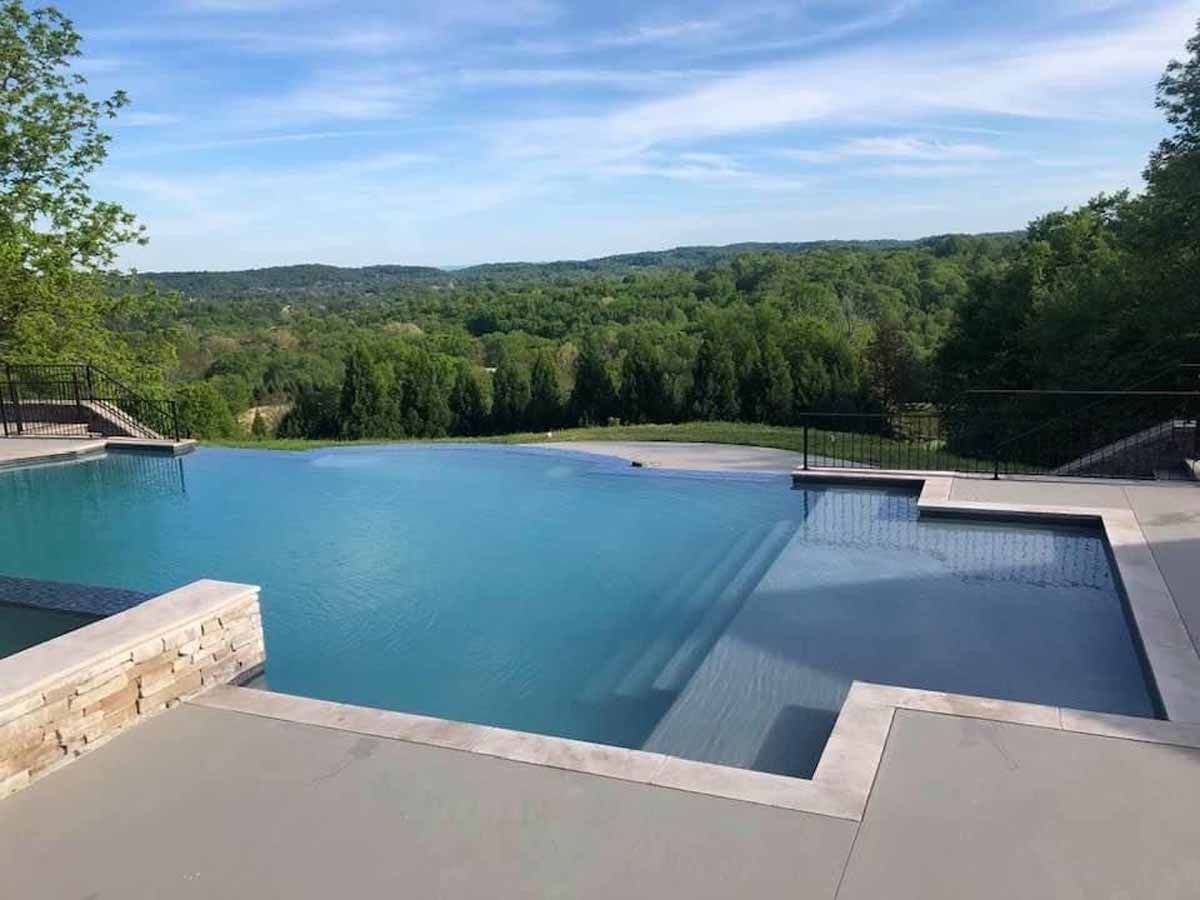 A large swimming pool with a view of a forest.