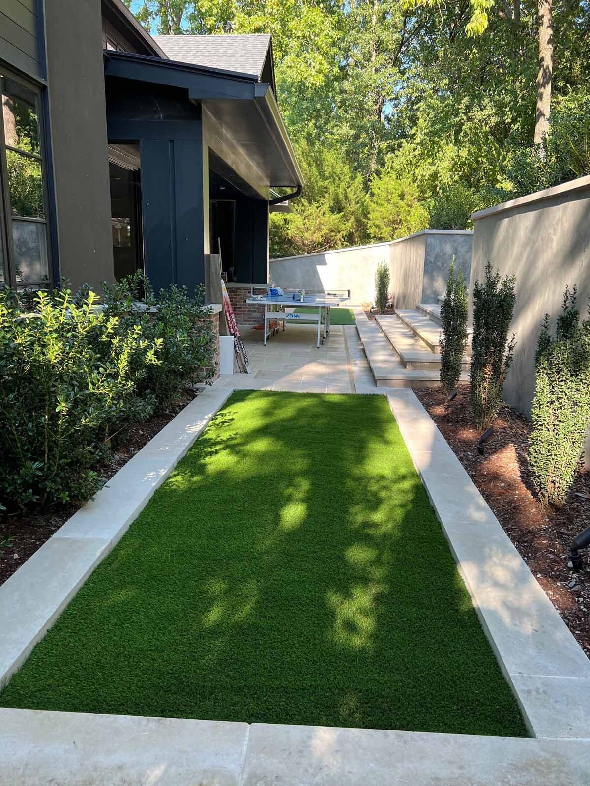 A lawn with a concrete walkway leading to a house.