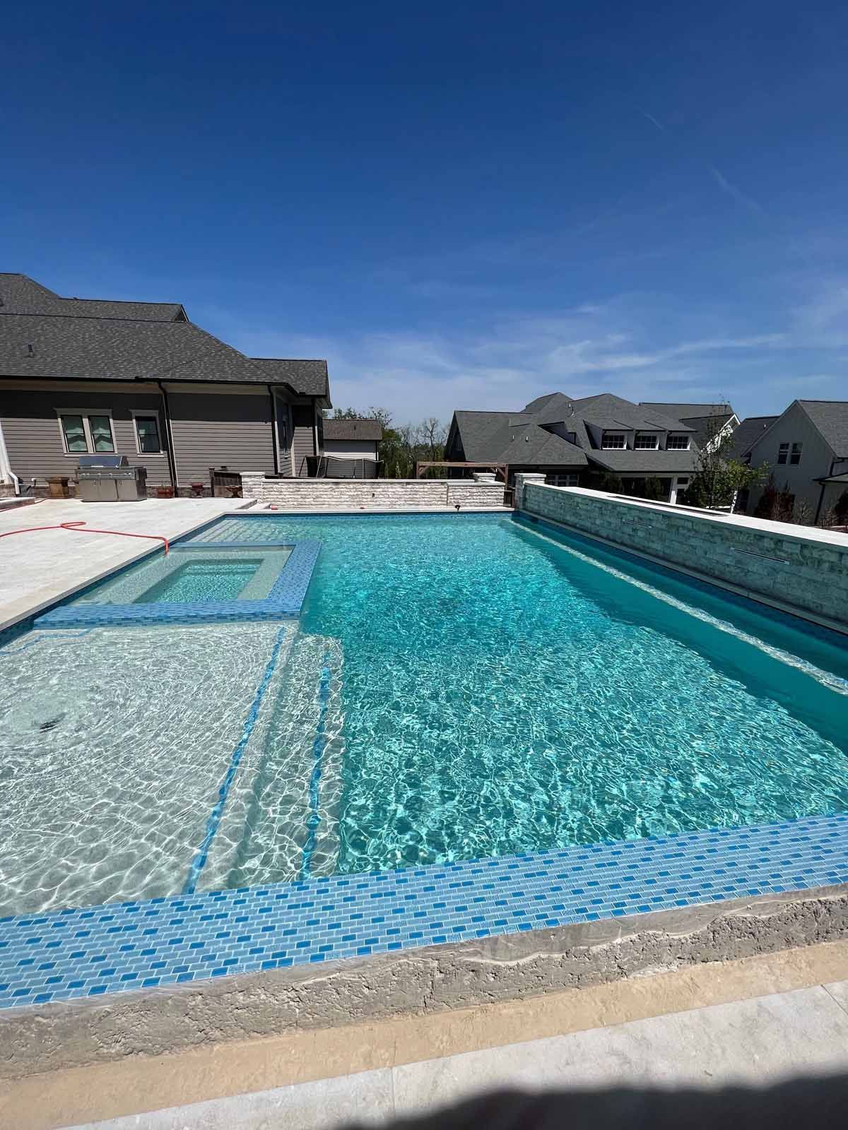 A large swimming pool is surrounded by houses on a sunny day.