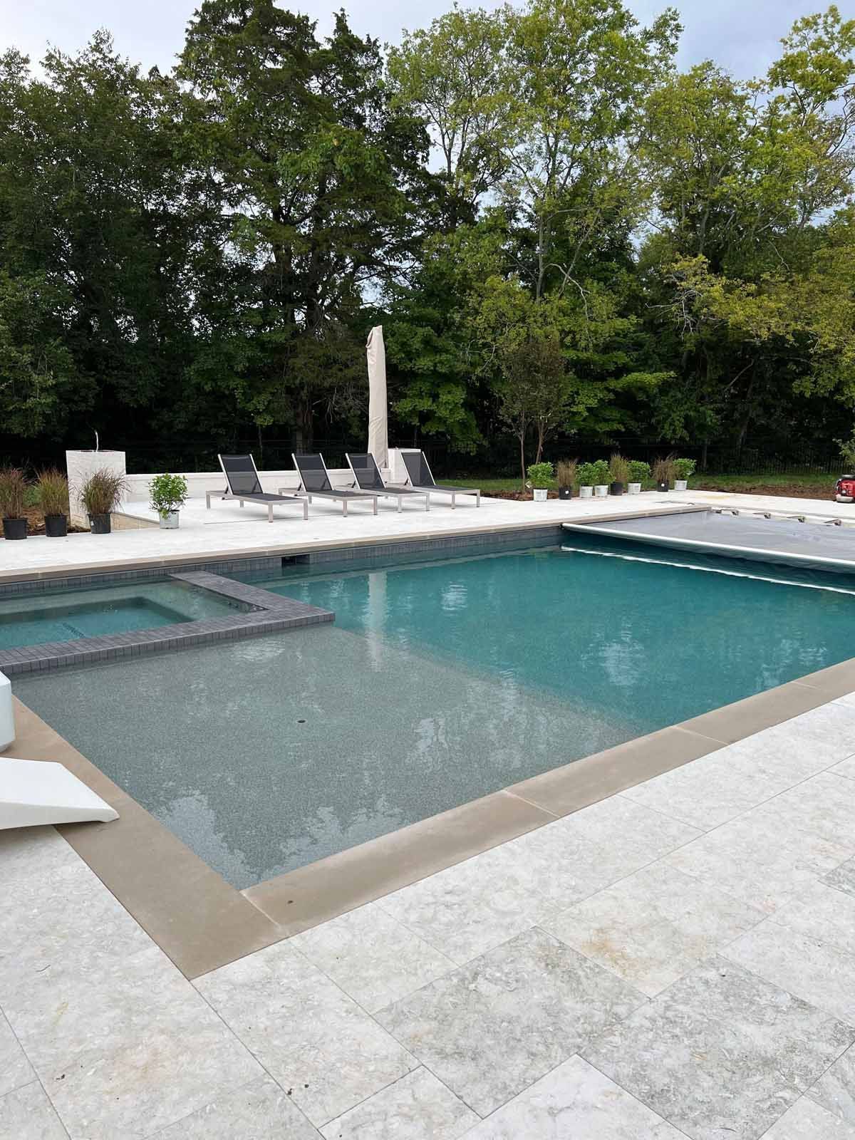 A large swimming pool surrounded by chairs and trees