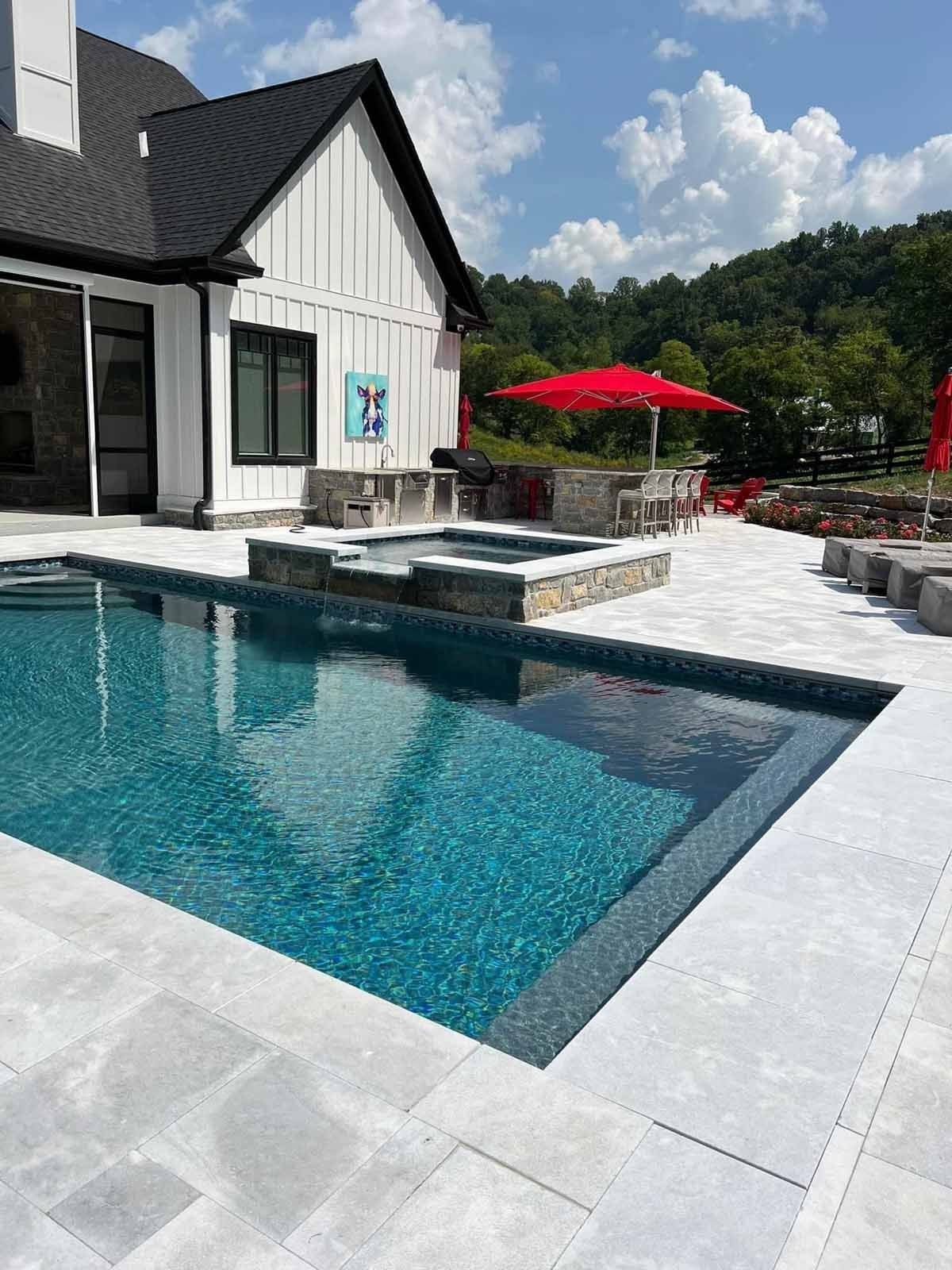 There is a large swimming pool in the backyard of a house.