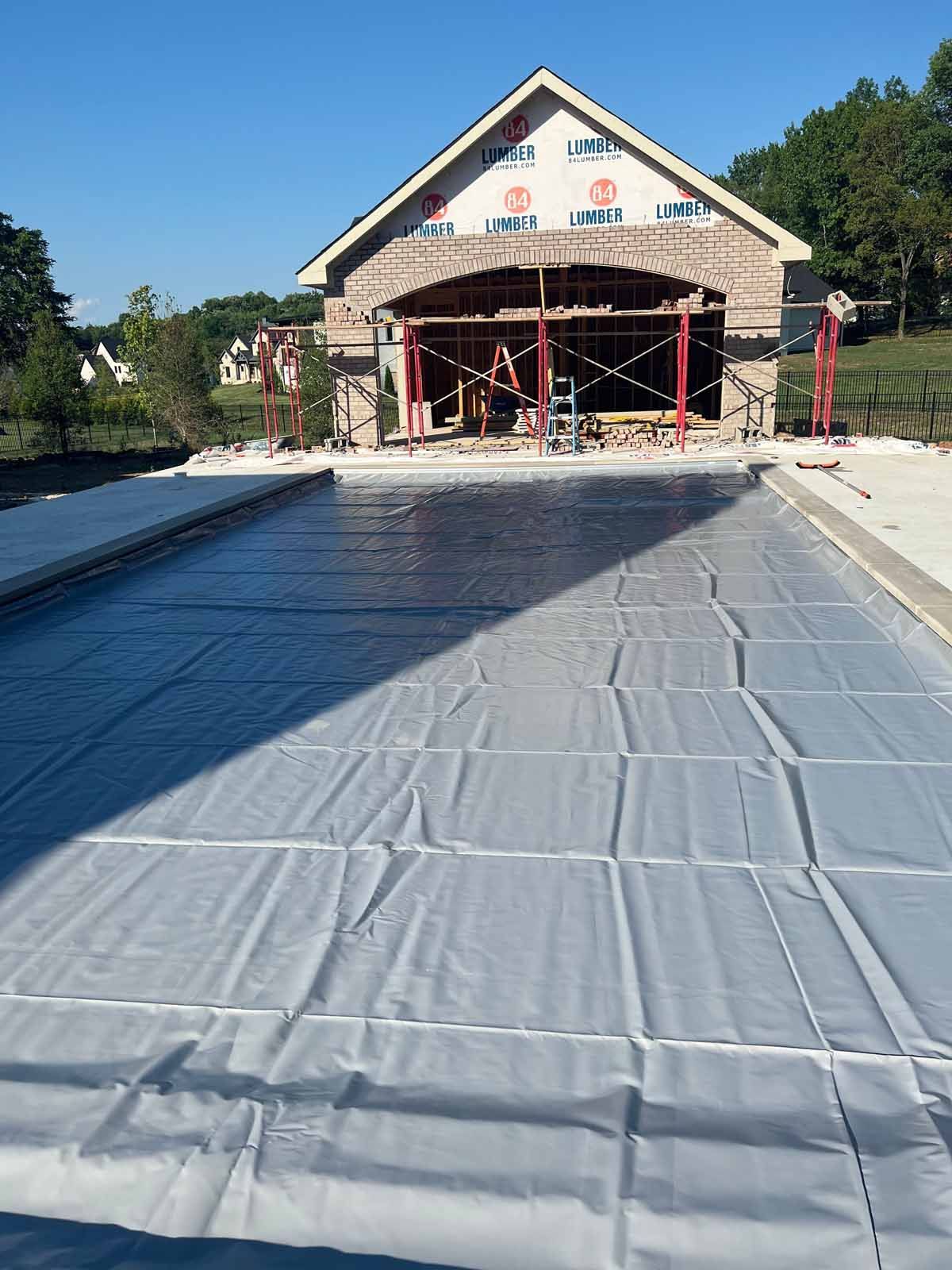 A large swimming pool is under construction in front of a building