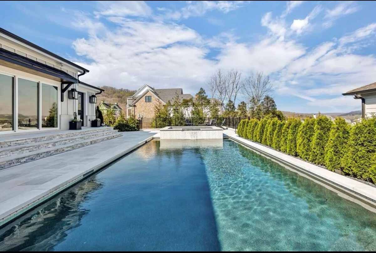 There is a large swimming pool in the backyard of a house.