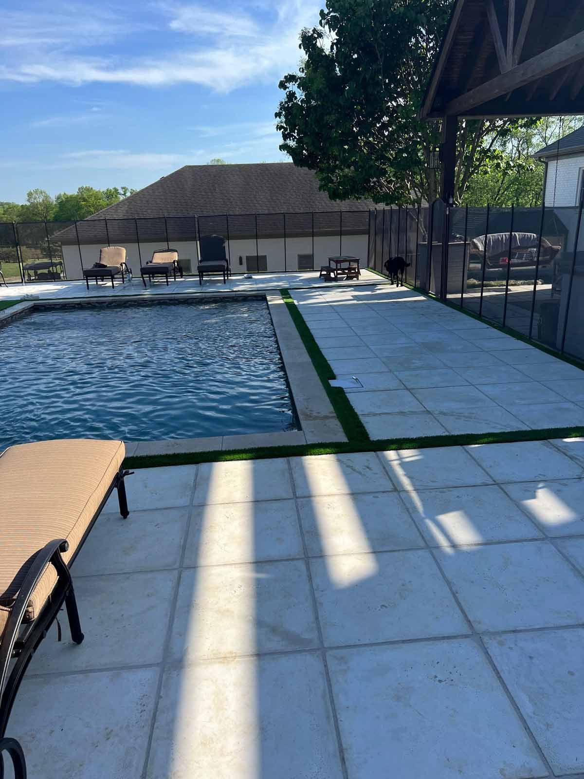 A large swimming pool is surrounded by a white tiled patio