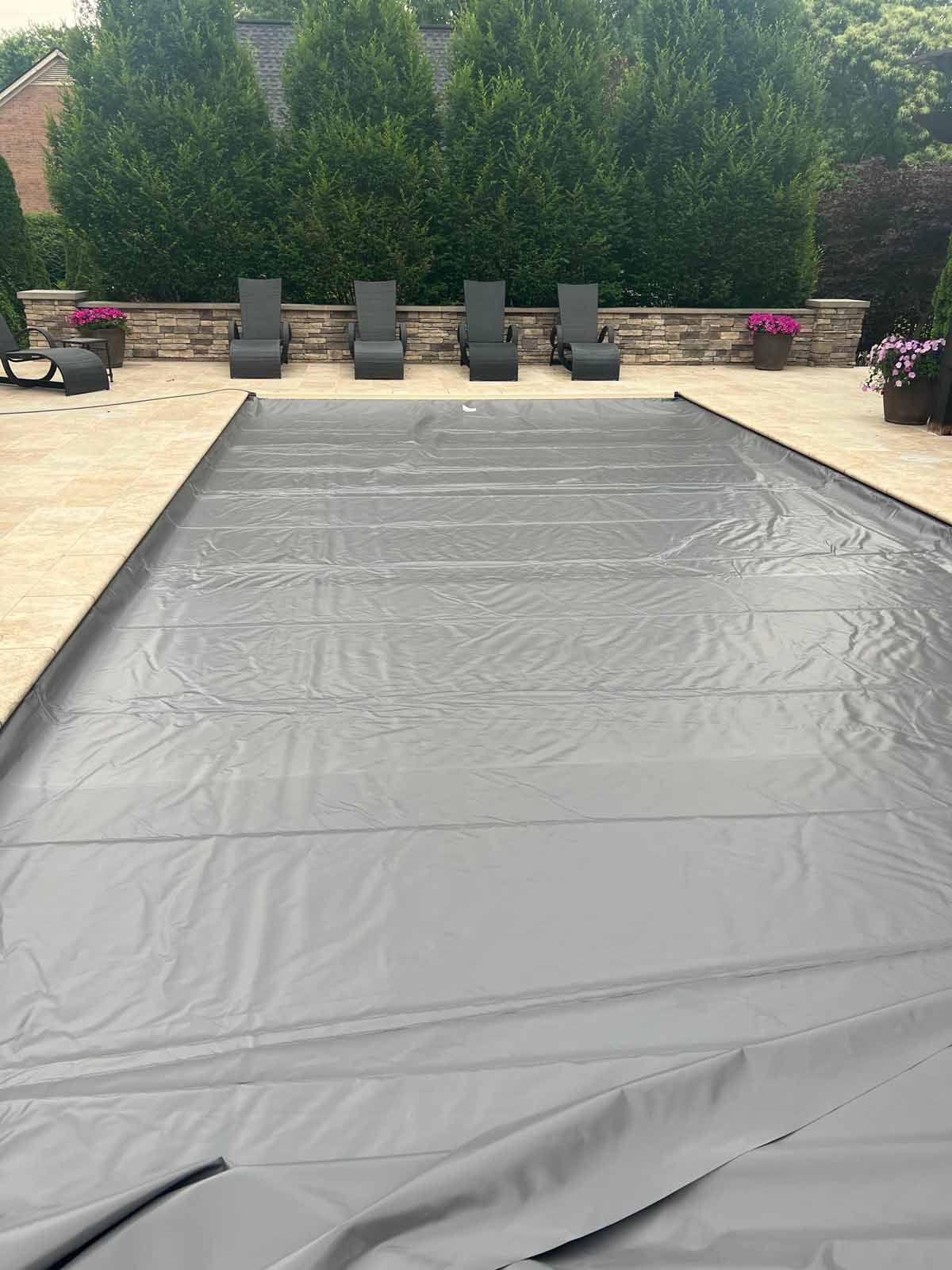 A swimming pool with a cover on it and chairs around it.