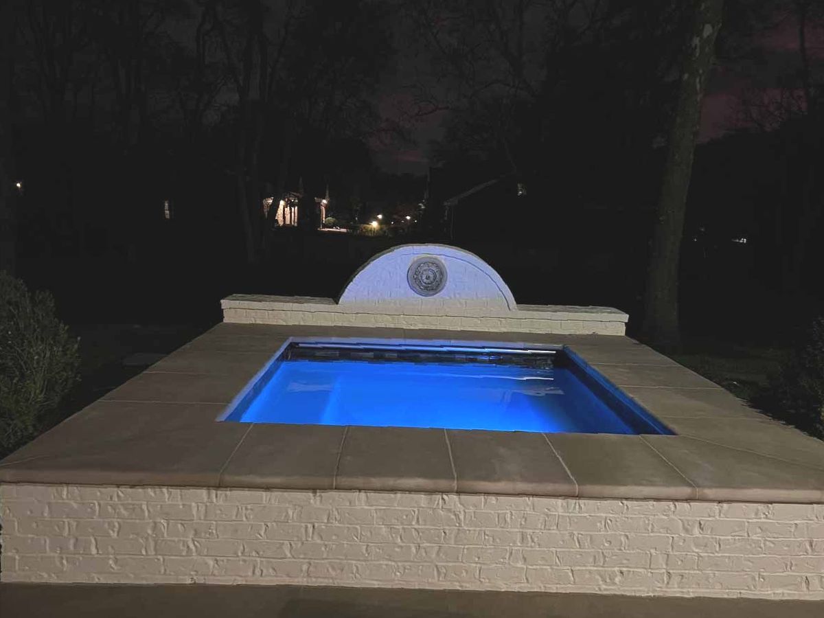 A small swimming pool is lit up at night.