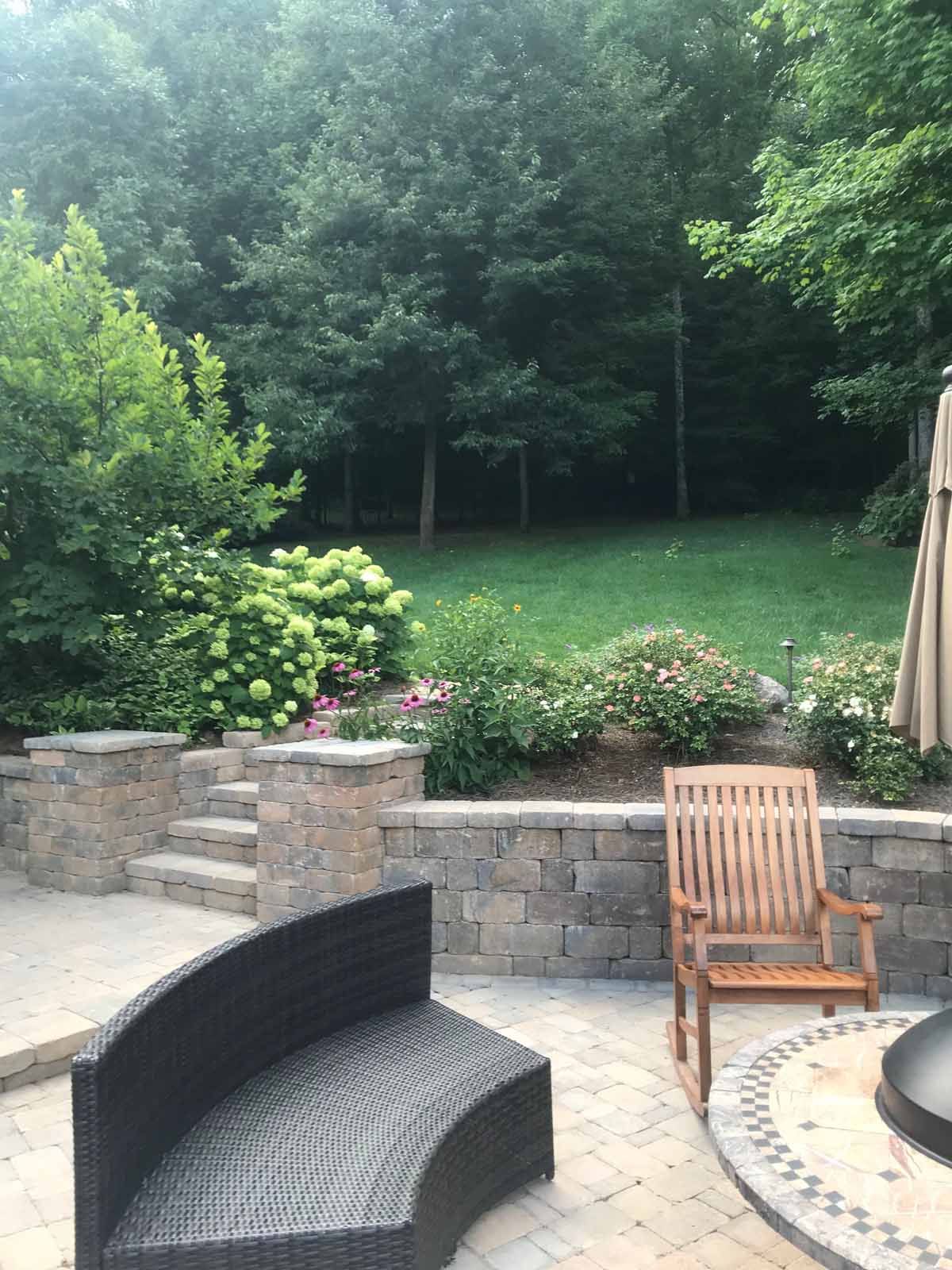 A patio with a couch , chair , table and umbrella.