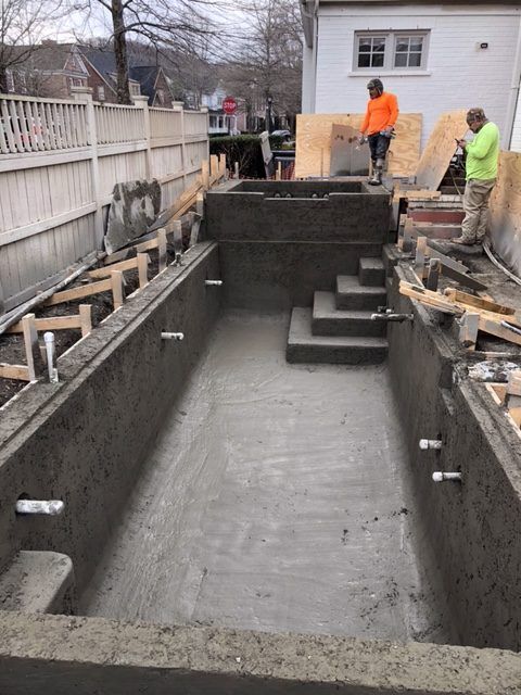 A swimming pool is being built in the backyard of a house