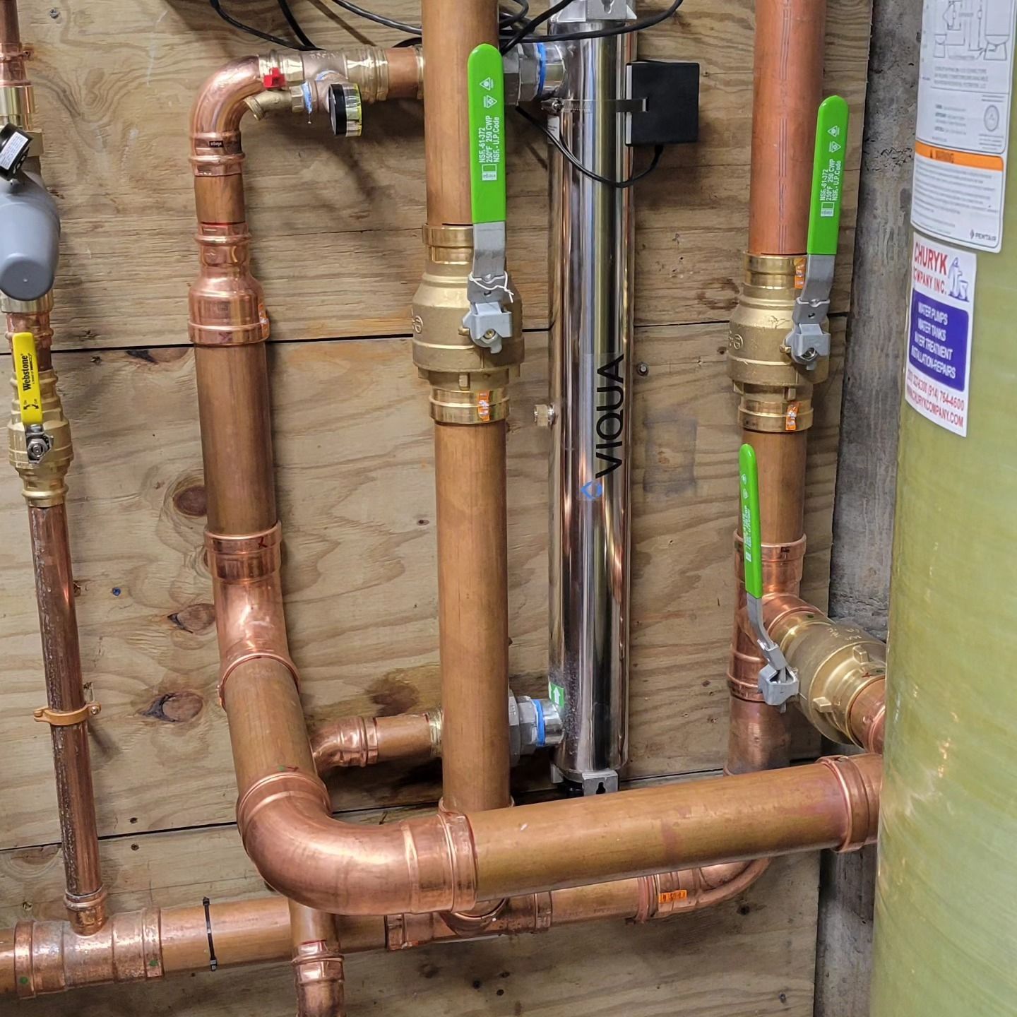 Copper pipes are connected to a water heater in a room.