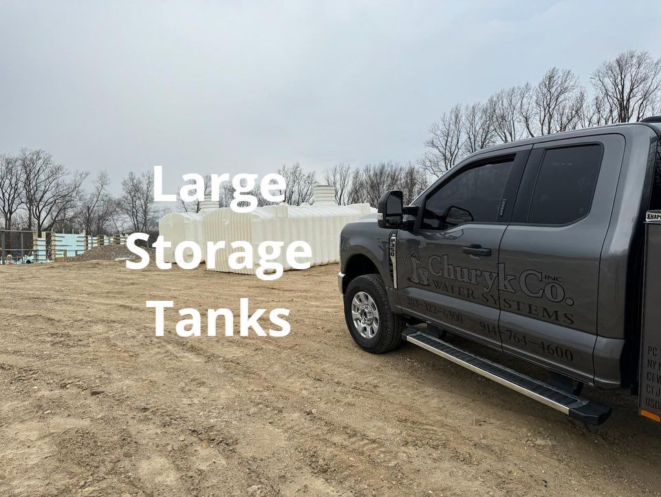 A large storage tank is parked in a dirt field.