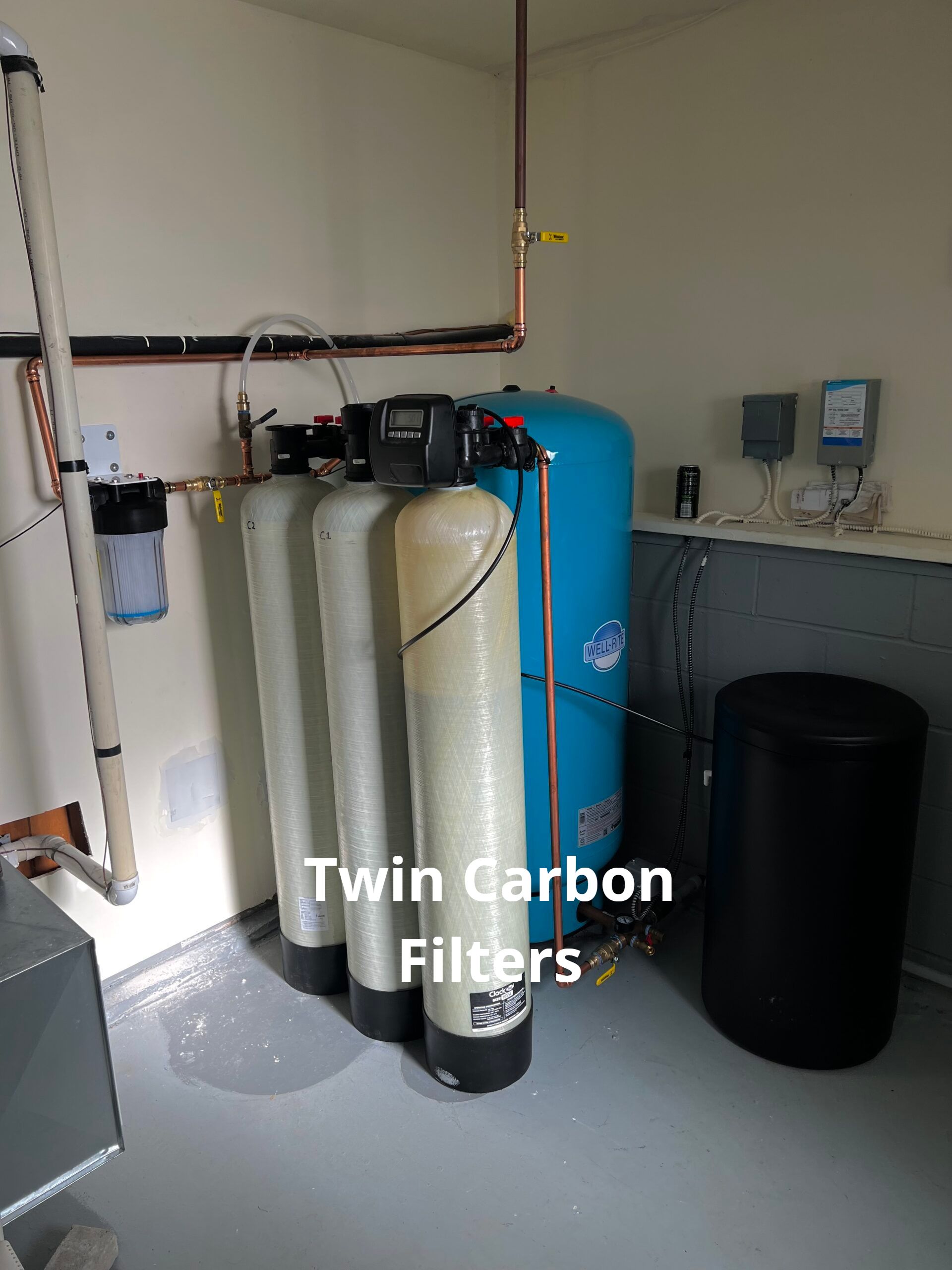 A room with three twin carbon filters and a blue tank