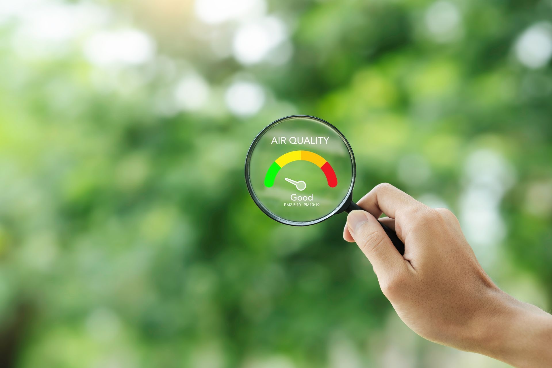 Hand holding a magnifying glass over a green gauge on a blurred background