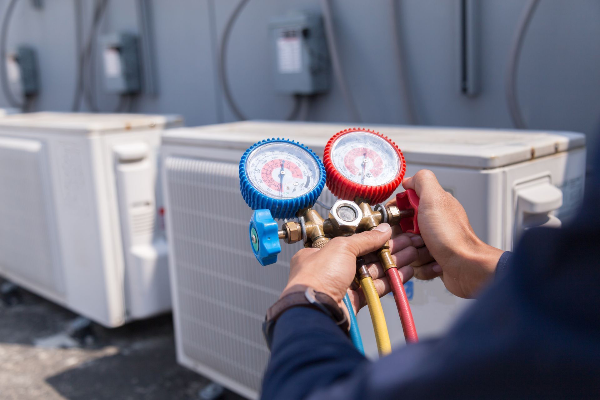 Technician testing HVAC unit with manifold gauges and colored hoses outdoors