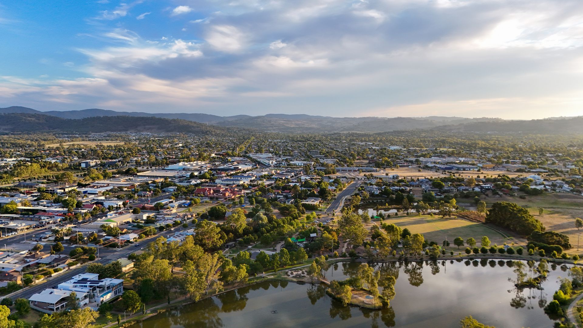 Scaffolding covers the side of a brick building between two skyscrapers, viewed from below, on a clear day.