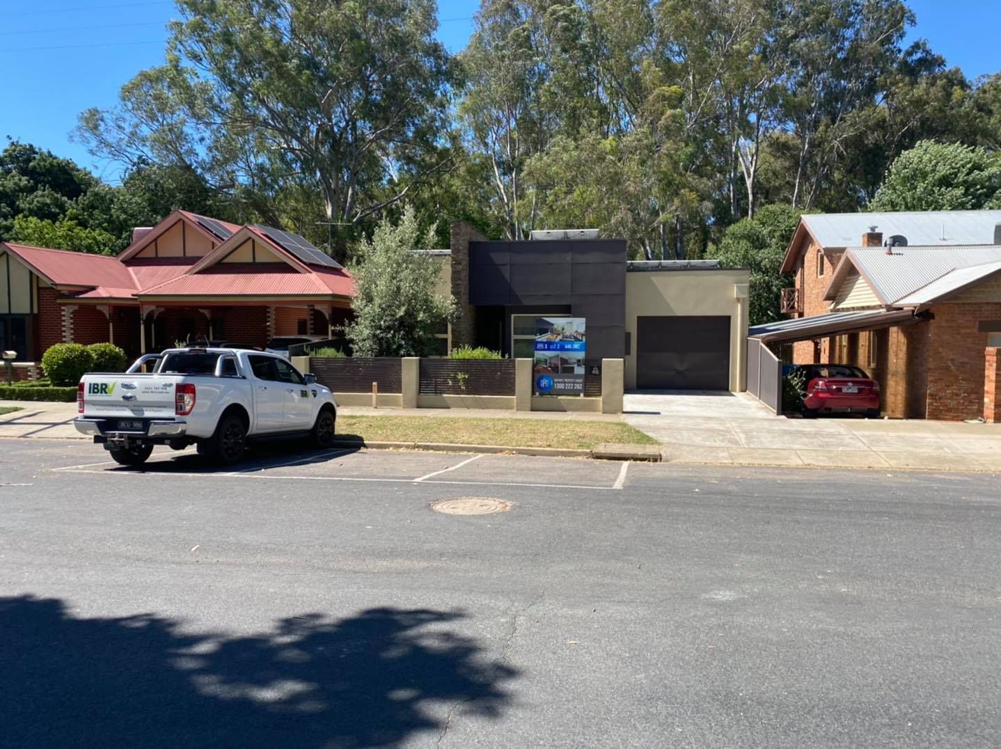 A white pickup truck parked on a street in front of a modern house and other houses.