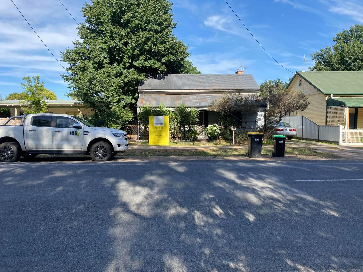 A weathered house with a yellow sign and a white truck parked in front.