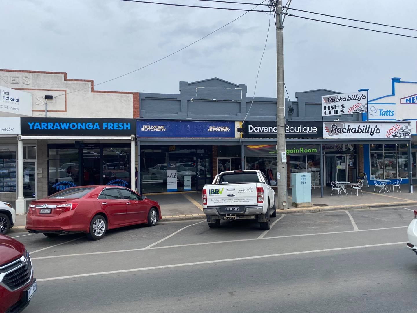 Shops on a street in Yarrawonga, Australia. Cars parked out front. Cloudy sky.
