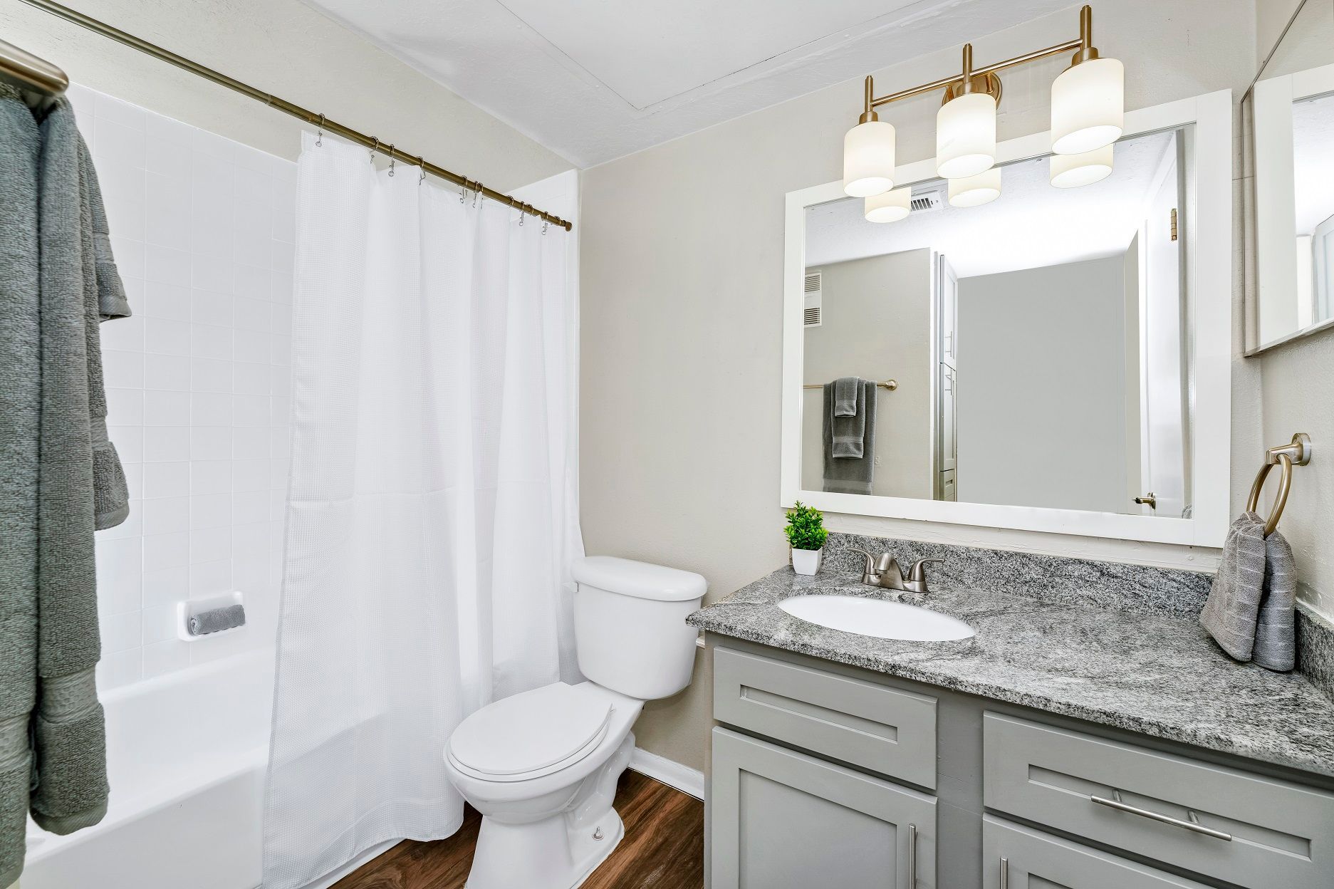 Bathroom with a white tub, toilet, gray vanity, and a white framed mirror at Timberlake in Altamonte Springs, FL.