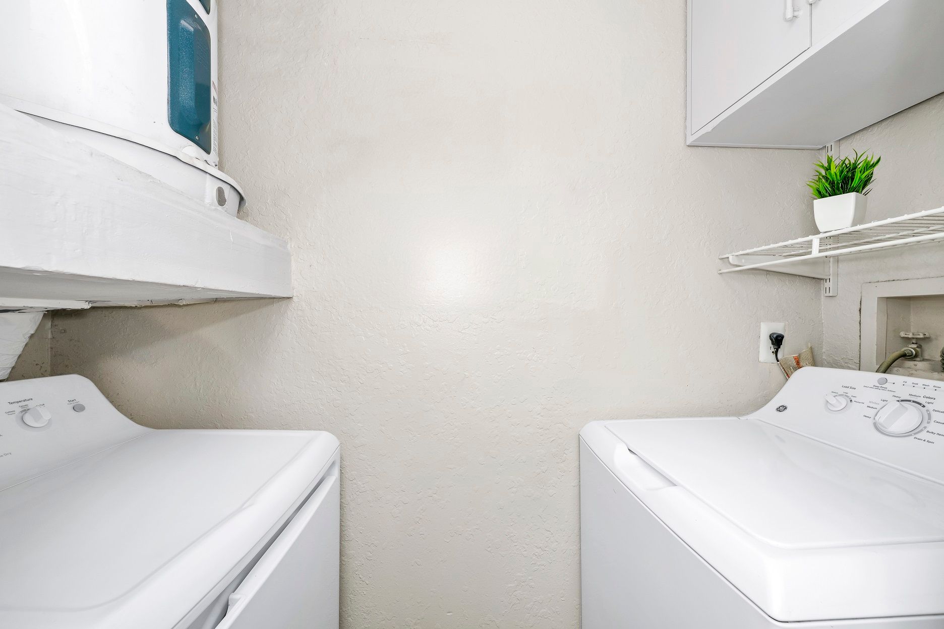White washer and dryer in a laundry room, with shelves and a small plant at Timberlake in Altamonte Springs, FL.