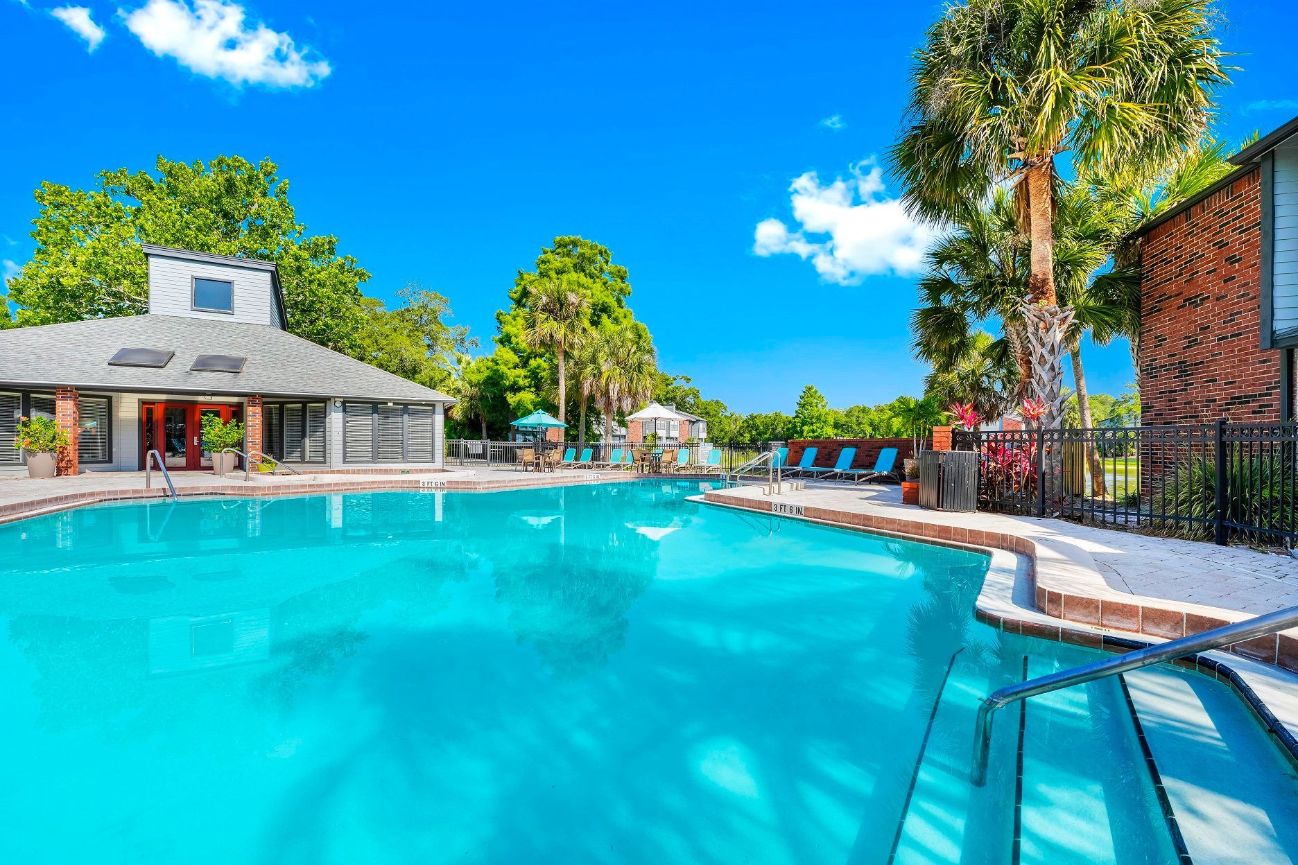 Swimming pool at apartment complex with a clubhouse and sunny blue sky at Timberlake in Altamonte Springs, FL.