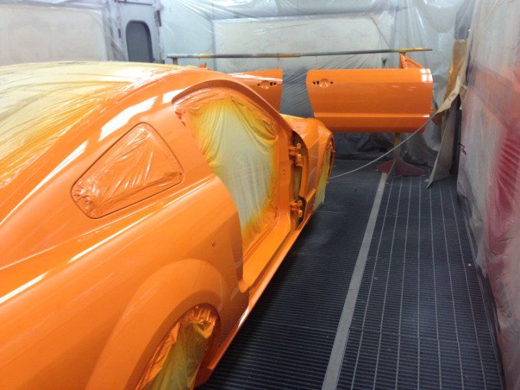 una macchina verniciata di arancione in un forno di una carrozzeria