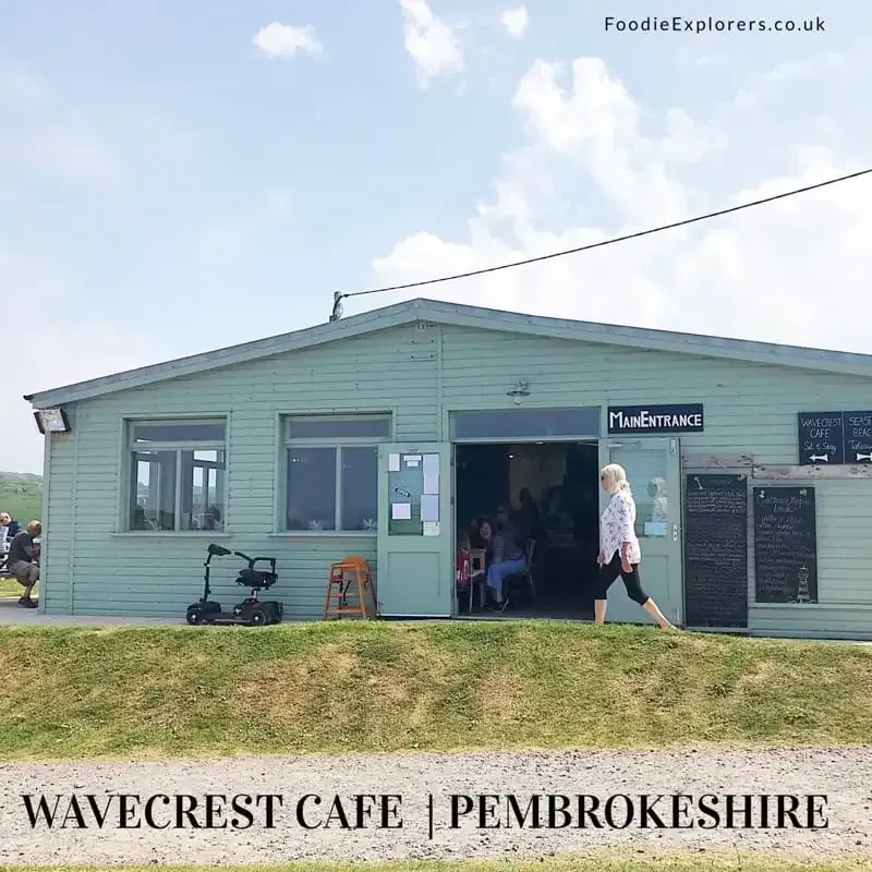A green building with a sign that says wavecrest cafe pembrokeshire