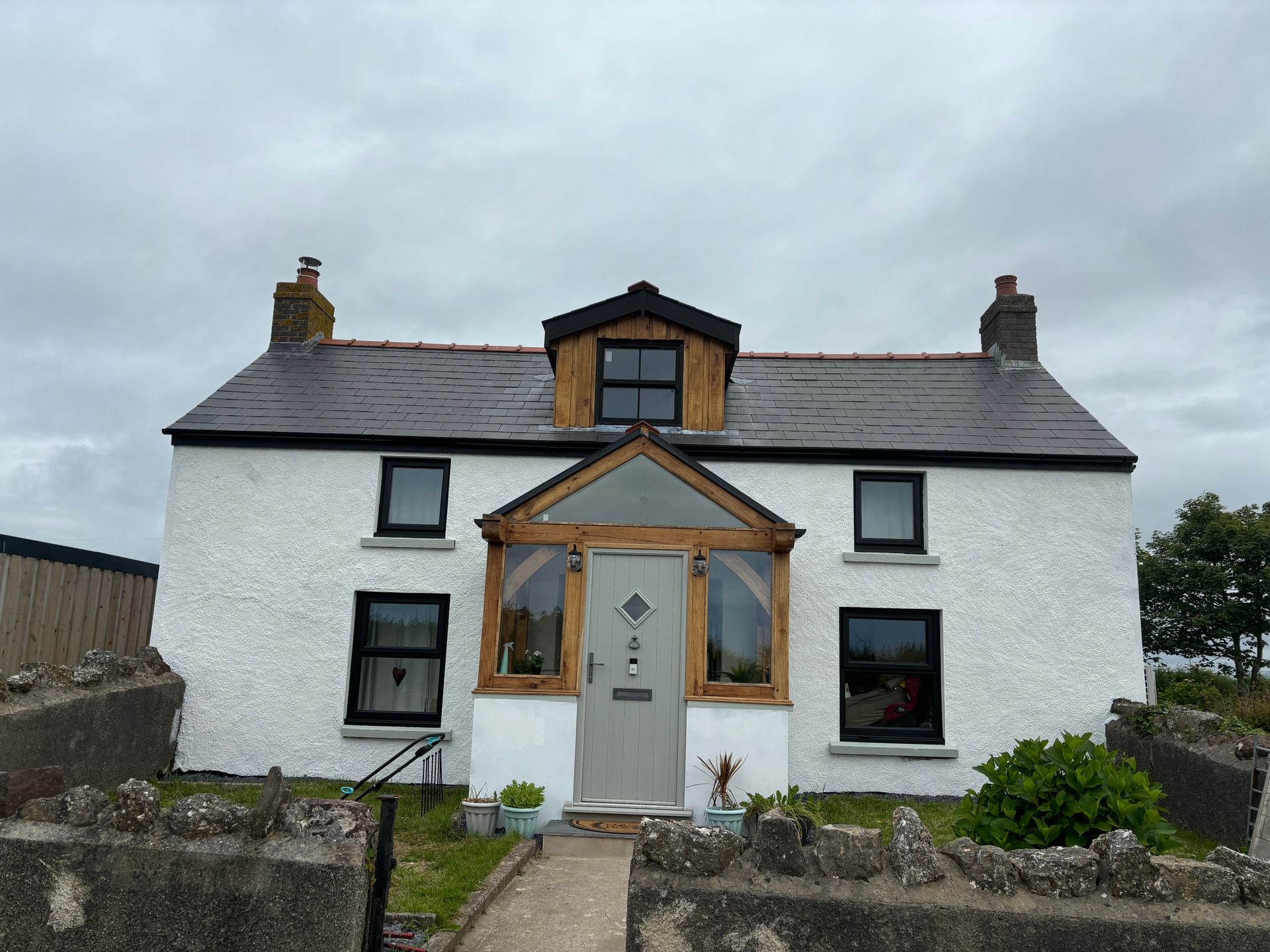 A white house with a slate roof and a wooden porch.