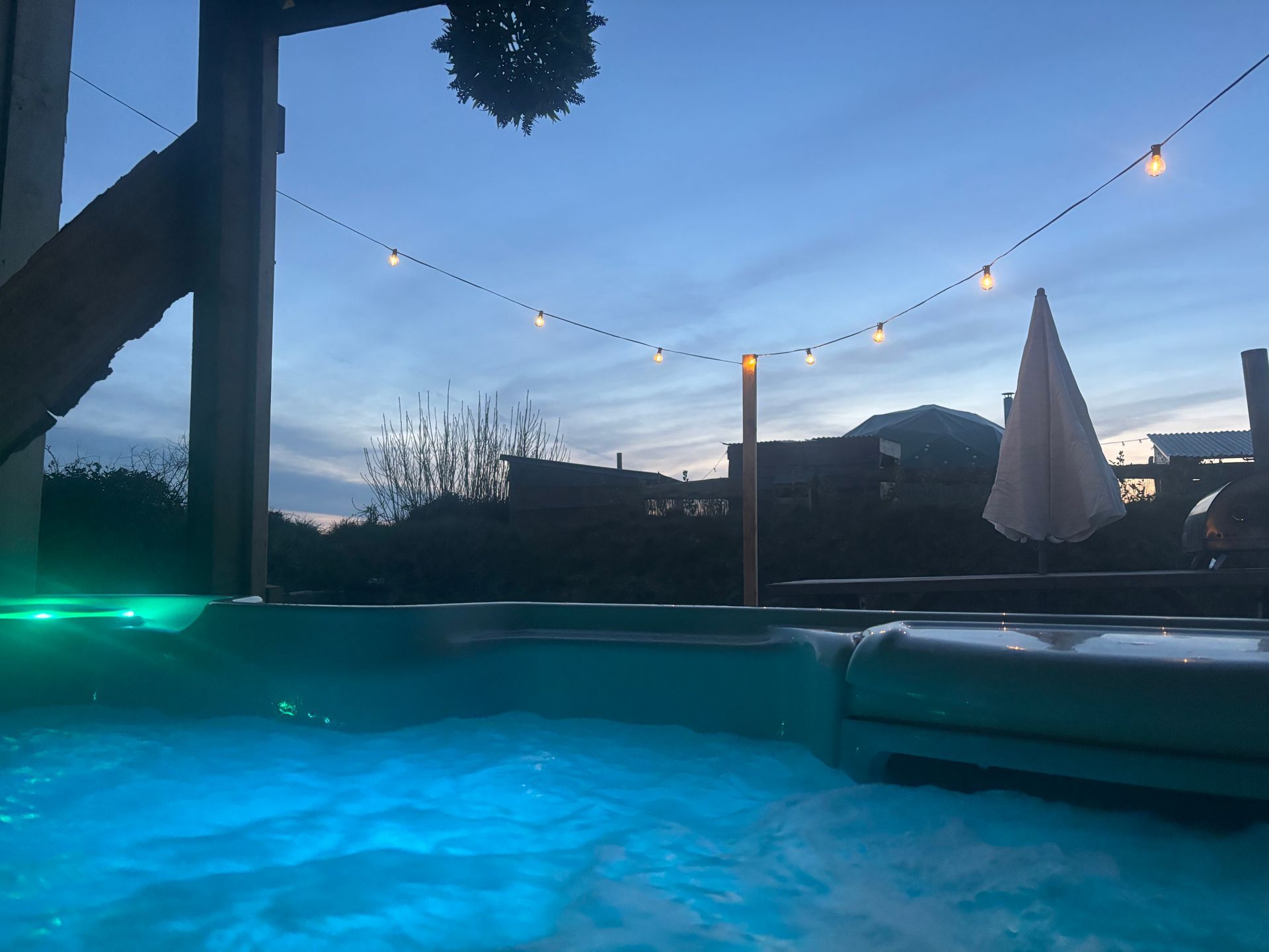 A hot tub filled with blue water is lit up at night