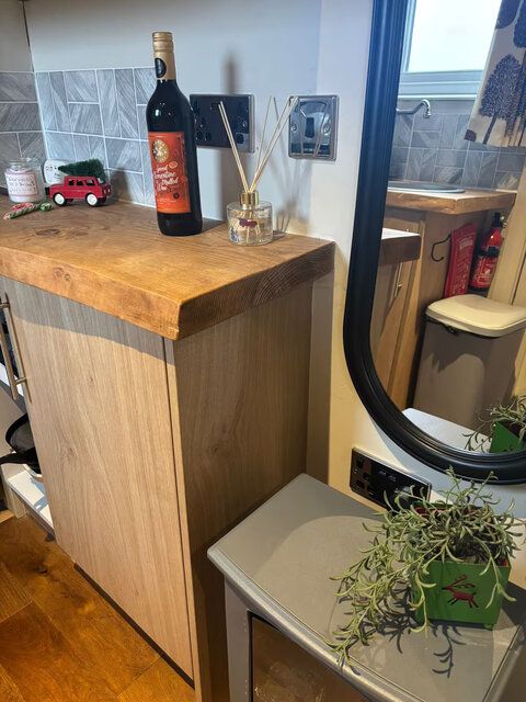 A bottle of wine is sitting on a wooden counter next to a mirror.