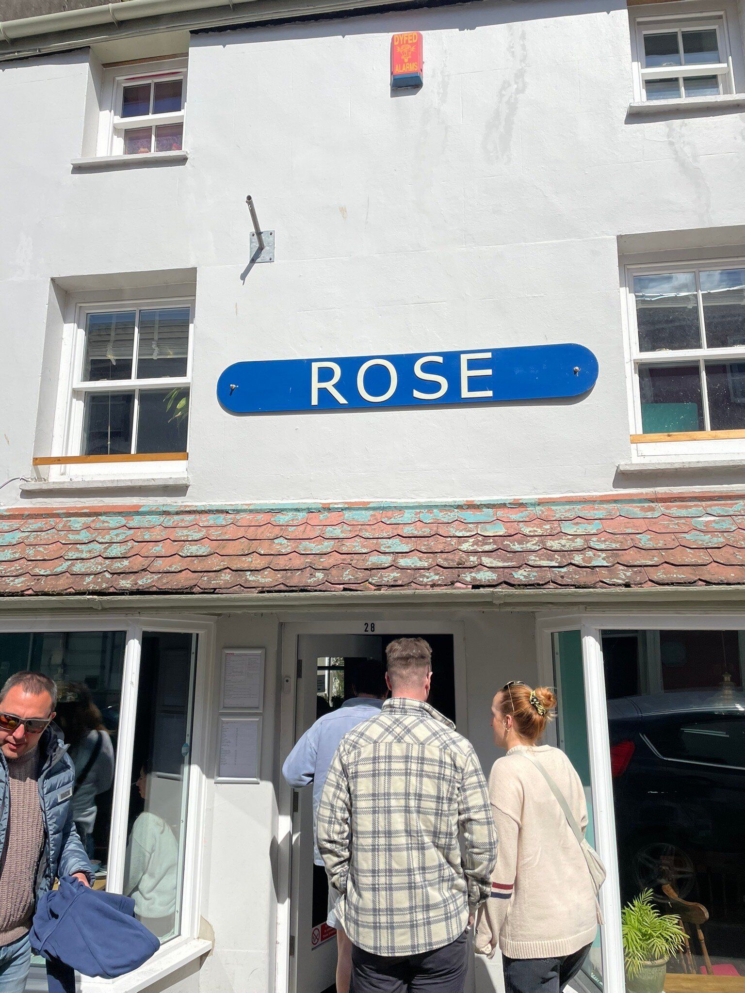 A group of people are standing outside of a store called rose