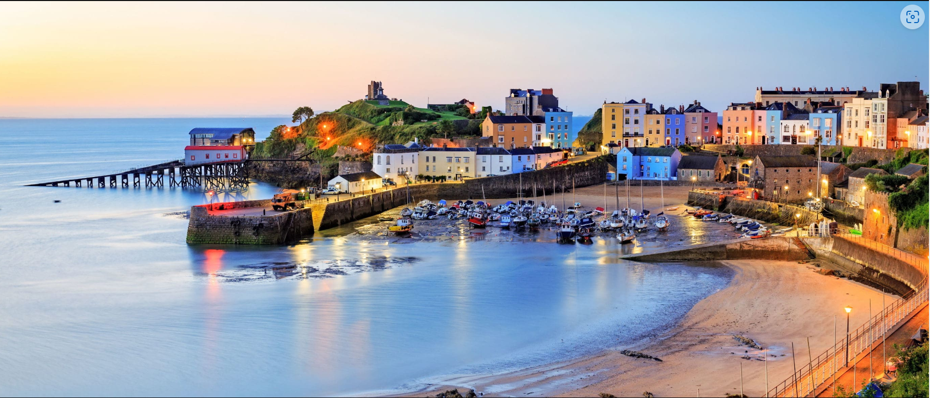 An aerial view of a harbor with a city in the background and a beach in the foreground.
