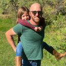A man is carrying a little girl on his shoulders.