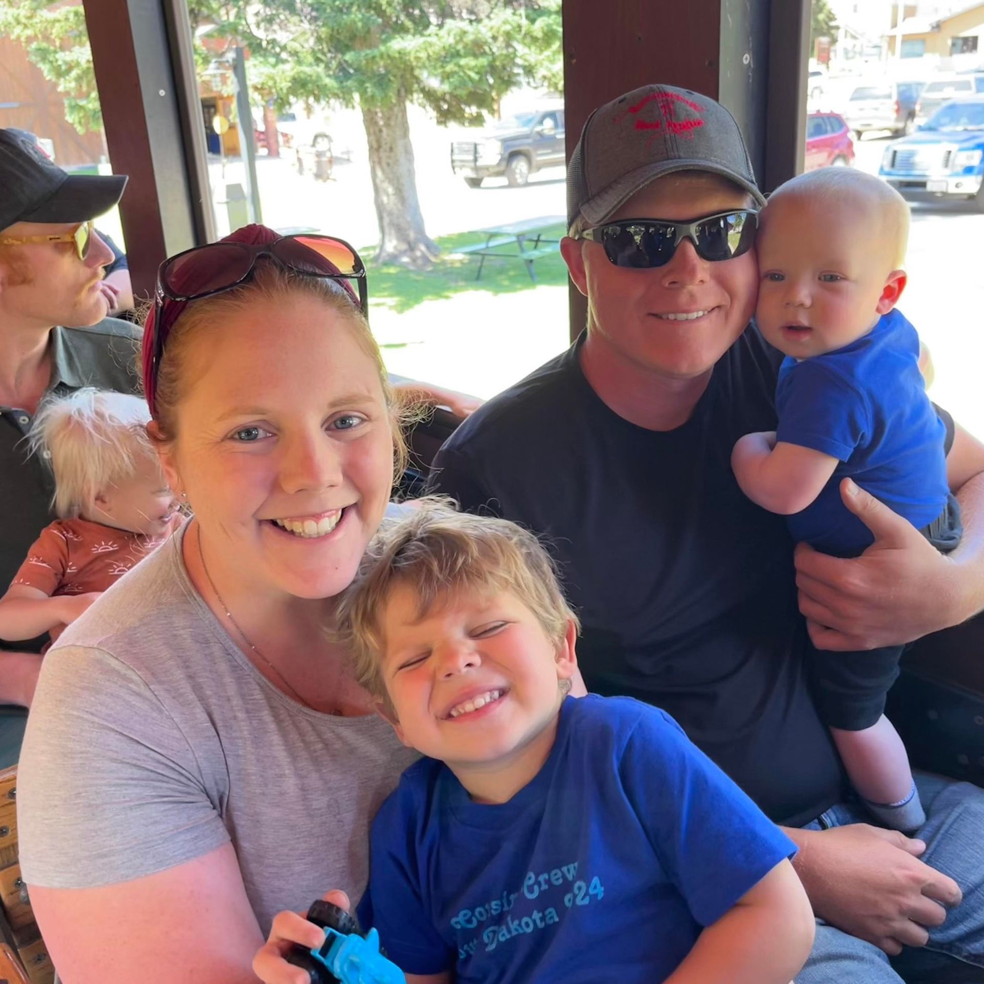 A man wearing sunglasses is holding a baby in his arms