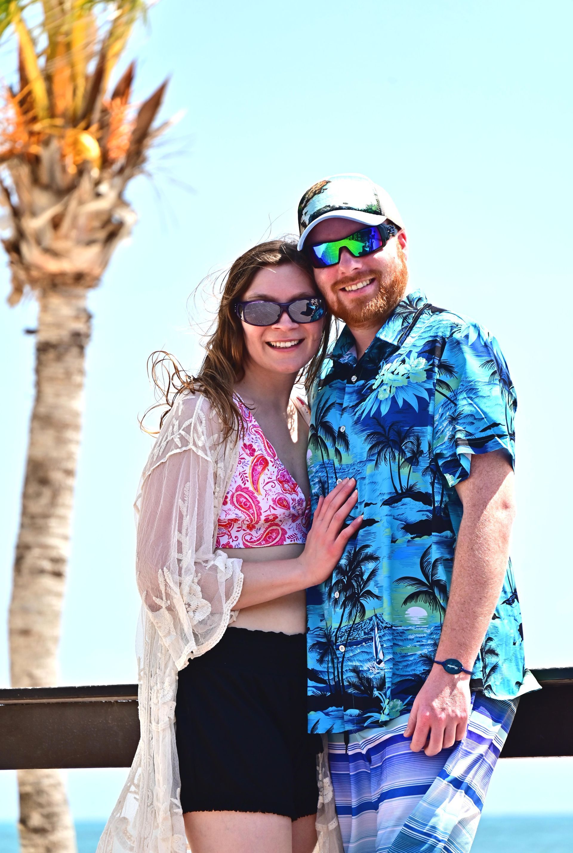 A man and a woman are posing for a picture on the beach.