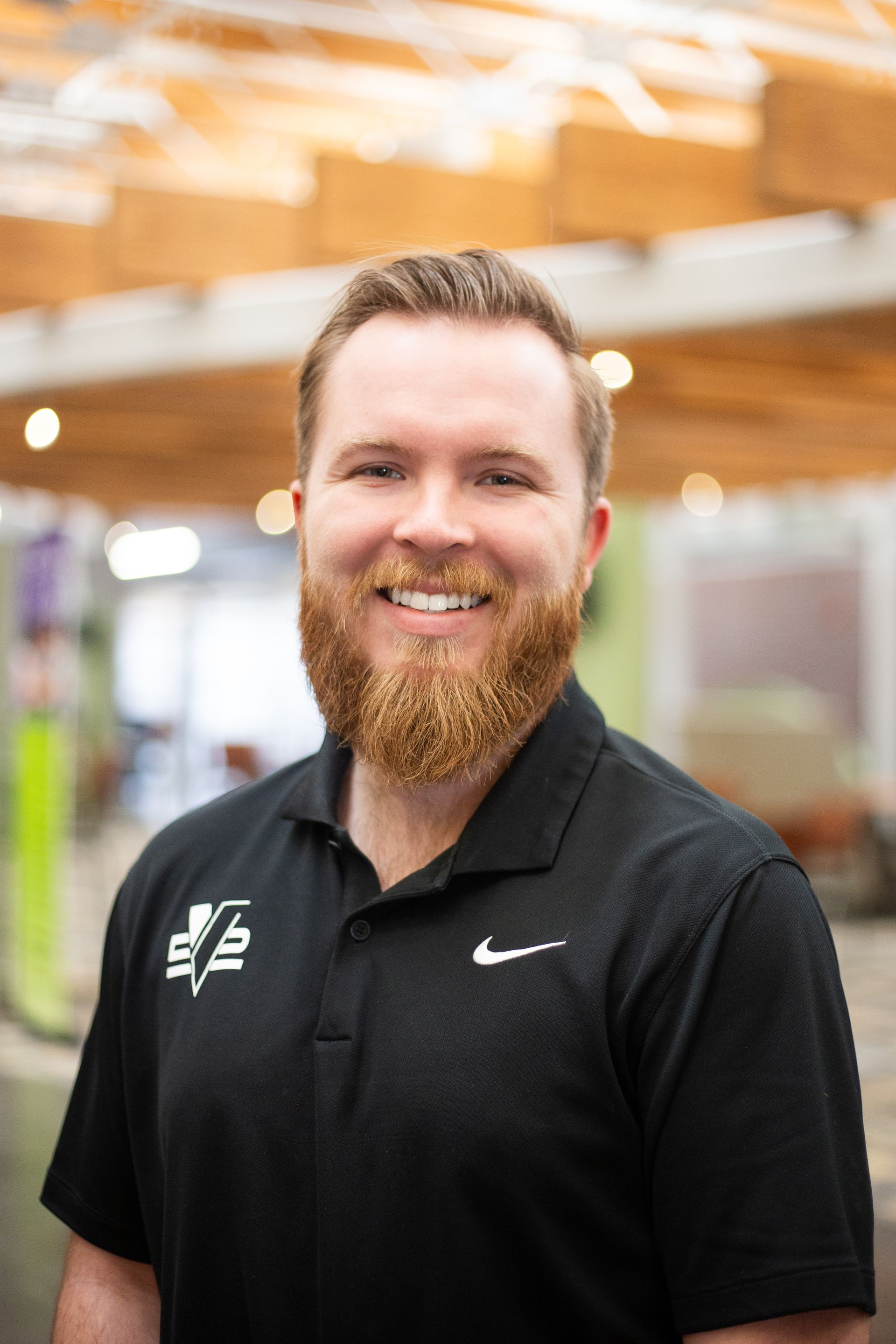 Family posing by a turquoise pond with waterfall. Woman holds a child, man stands next to them. Outdoors, overcast.