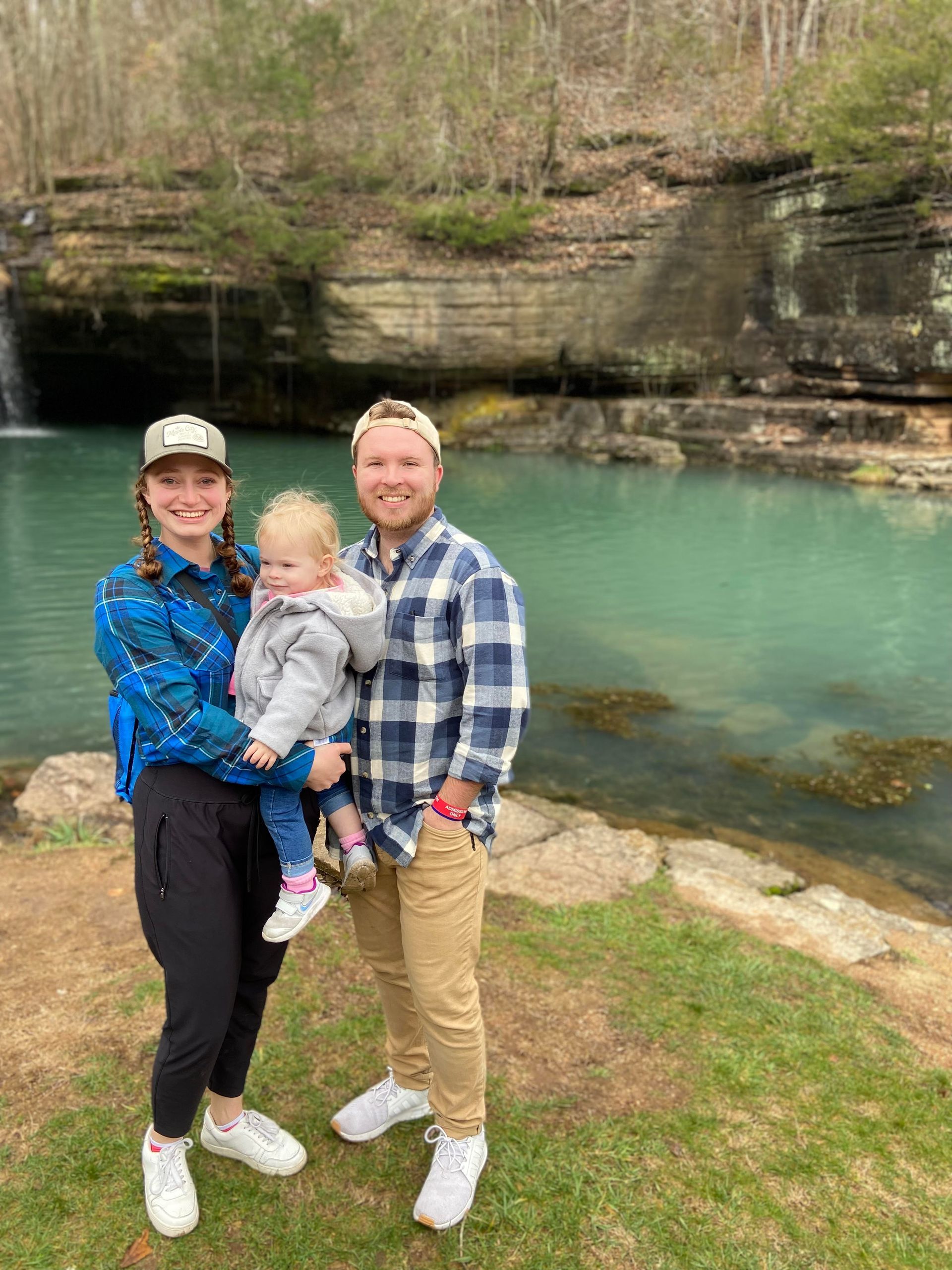 A family is posing for a picture in front of a waterfall.