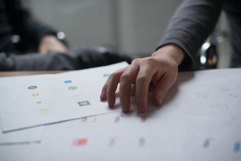A person 's hand is reaching for a piece of paper on a table.