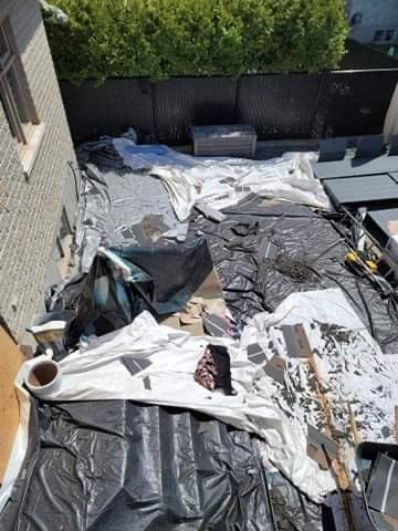 Une cour arrière résidentielle en rénovation, recouverte de bâches en plastique noires et blanches et de débris de construction.