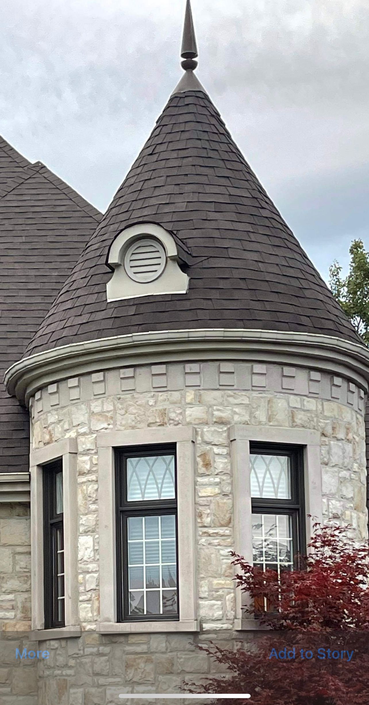 Une tourelle de château en pierre, coiffée d'un toit conique sombre, percée d'une petite lucarne et de deux fenêtres cintrées, se détachant sur un ciel nuageux.