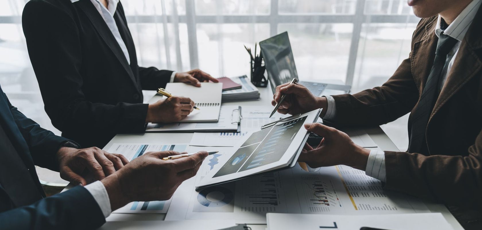 Financial reports and a laptop on a conference room table
