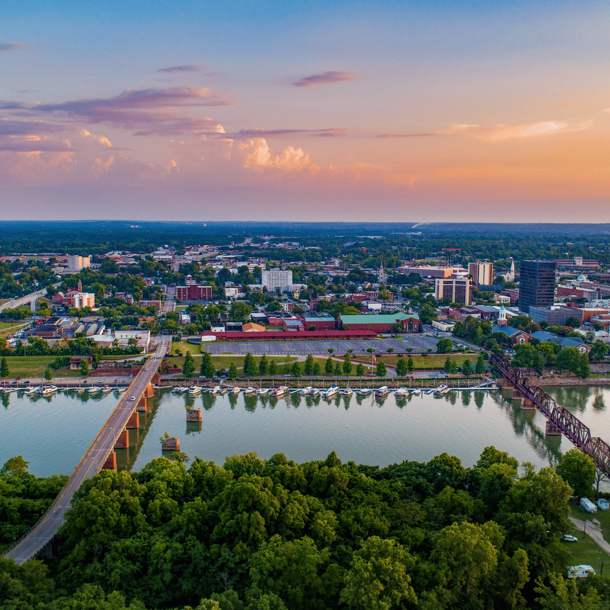 Aerial view of a city with a bridge over a lake surrounded by trees.