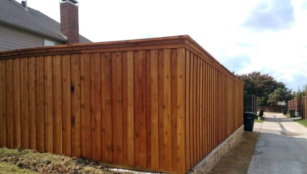 Wooden fence with brown planks in front of a house next to an alley.