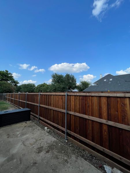 Wooden fence against a blue sky with fluffy clouds.